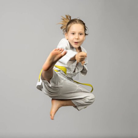 Photo for Girl performs martial arts flying kick, studio shot - Royalty Free Image
