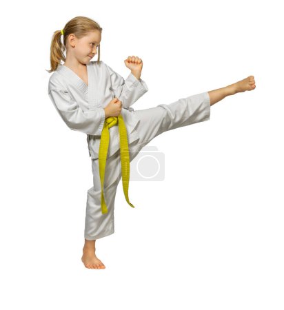 Téléchargez les photos : Enfant pratiquant les arts martiaux effectue un coup de pied latéral, isolé sur blanc - en image libre de droit