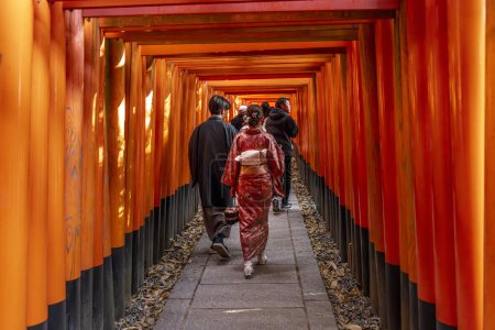 Foto de KYOTO / JAPÓN - 28 de noviembre de 2023: La gente pasa bajo los torii del templo inari de Fushimi - Imagen libre de derechos