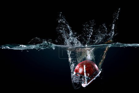 Téléchargez les photos : Casque de football américain dans l'eau. Techniques mixtes - en image libre de droit