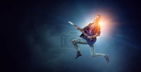 Photo for Young and beautiful rock girl playing the electric guitar. Mixed media - Royalty Free Image