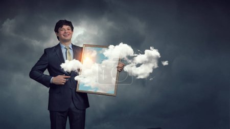 Téléchargez les photos : Homme tenant cadre avec ciel bleu et nuages.Techniques mixtes - en image libre de droit