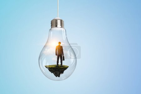 Photo for Business man standing and holding briefcase inside a light bulb. Mixed media - Royalty Free Image