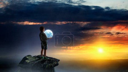 Téléchargez les photos : Petit garçon tenant la lune la nuit. Techniques mixtes - en image libre de droit