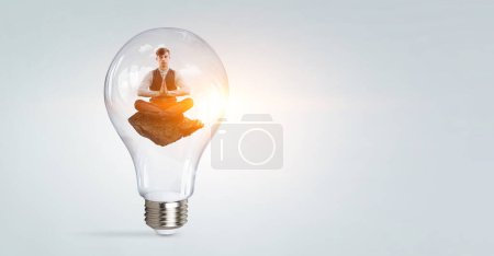 Téléchargez les photos : Homme d'affaires méditant à l'intérieur de l'ampoule. Techniques mixtes - en image libre de droit