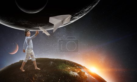 Téléchargez les photos : Joyeux gamin jouant avec un avion en papier. Techniques mixtes - en image libre de droit
