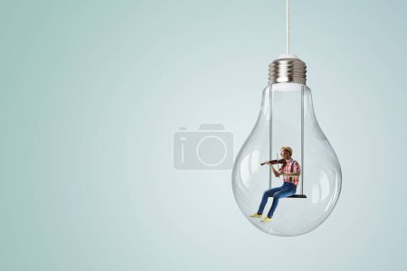Photo for Man plays violin sitting on light bulb. mixed media - Royalty Free Image