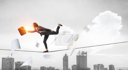 Foto de Imagen de empresaria balanceándose sobre cuerda. Concepto de riesgo. Medios mixtos - Imagen libre de derechos