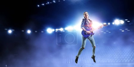 Photo for Young and beautiful rock girl playing the electric guitar. Mixed media - Royalty Free Image