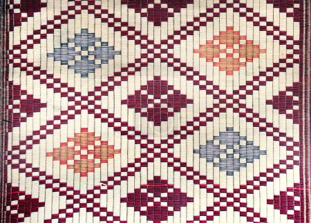 Téléchargez les photos : Tapis de sisal avec des motifs géométriques asiatiques traditionnels. Tapis en jute fait main avec ornement de couleur rouge, bleue, blanche et jaune - en image libre de droit