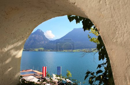Téléchargez les photos : Vue sur le lac Wolfgangsee par la fenêtre dans le mur médiéval de la forteresse, Autriche. Jour d'été - en image libre de droit
