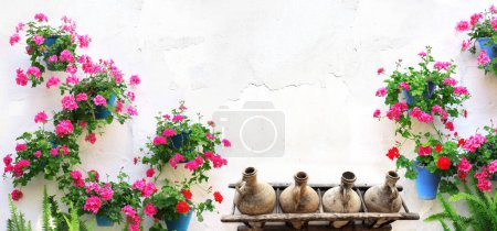 Photo for Horizontal banner with flowerpots with geranium and old pitchers on stucco wall. Pot of geranium and clay wine jars on white wall. Traditional mediterranean wall decoration of a village house - Royalty Free Image