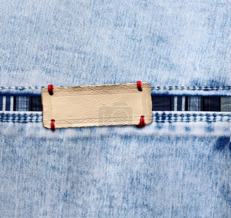 Photo for Blue denim texture with a seam and paper label. Light blue color denim jeans fabric and vintage paper tag. Mock up template. Copy space for text - Royalty Free Image