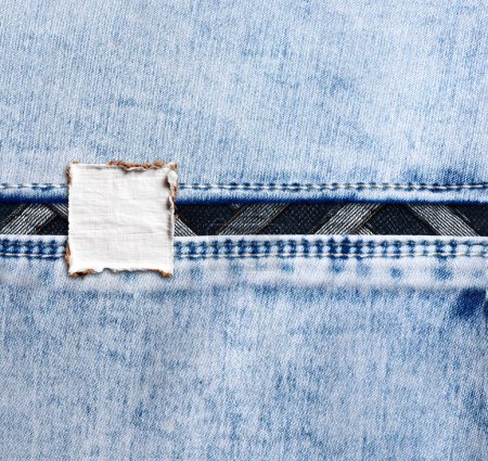 Photo for Blue denim texture with a seam and old label. Light blue color denim jeans material and vintage fabric tag. Mock up template. Copy space for text - Royalty Free Image