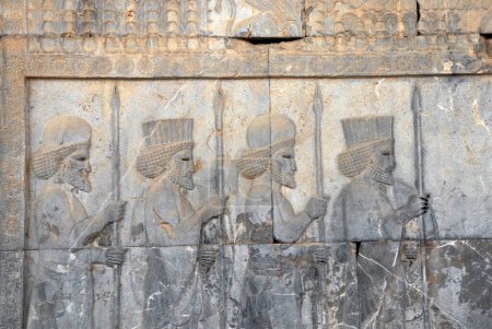 Téléchargez les photos : Ancien mur avec bas-relief avec quatre guerriers assyriens avec lances, Persépolis, Iran. Patrimoine mondial de l'UNESCO - en image libre de droit