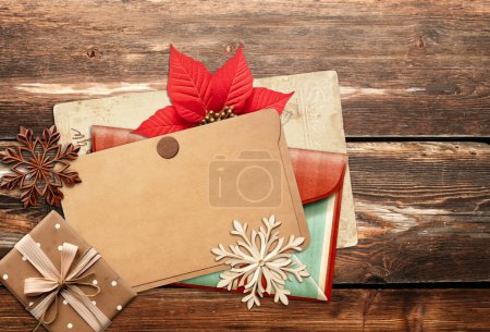 Photo for Christmas background with retro card, vintage envelope, poinsettia, gift and wooden snowflakes on old wooden boards. Nostalgic scrapbooking backdrop. Mock up template. Copy space for text - Royalty Free Image