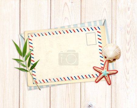 Photo for Vintage post card, envelope and souvenirs - green leaf, felt starfish, shell on old wooden boards. Retro postcard with decorative border. Horizontal vacation backdrop. Copy space for text - Royalty Free Image