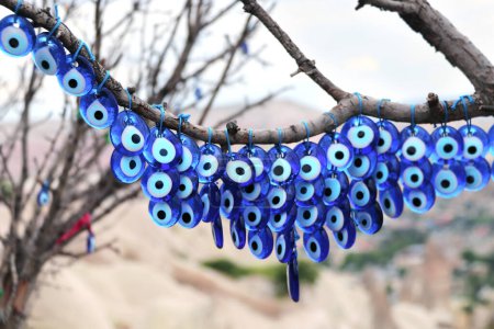 Téléchargez les photos : Nombreuses mascottes en verre - charmes d'yeux maléfiques suspendus à un arbre dans la vallée du Pigeon, en Cappadoce, Turquie - en image libre de droit
