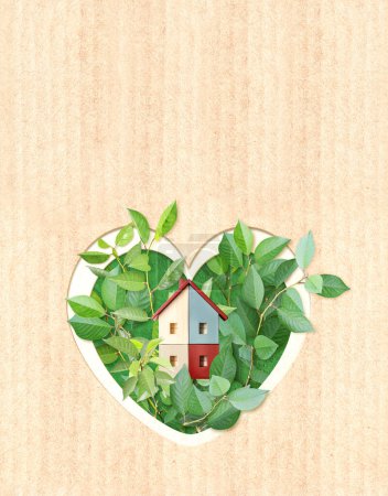 Eco friendly house. Wooden home model, heart shape hole and green leaves on cardboard texture. Ecology, go green, Green Energy, Renewable Power, environmental and conservation protection concept