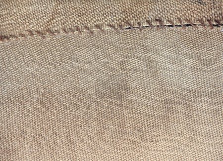 Two pieces of old burlap sewn together with thread. Horizontal background with rustic bag texture
