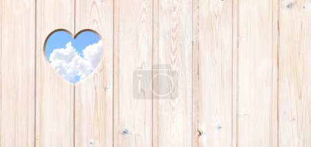 Téléchargez les photos : Trou en forme de coeur dans des planches en bois et ciel bleu avec des nuages. Trou en forme de coeur dans une clôture en bois. Vas-y vert. Écologie, ressources écologiques mondiales, concept d'éco et zéro déchet. Espace de copie pour le texte - en image libre de droit