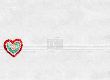 Horizontal Christmas backdrop with suede texture of ivory color and felt heart.  Can be used for scrapbooking winter design. Warm winter time background. Copy space for text