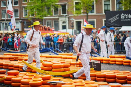 Foto de ALKMAAR, THE NETHERLANDS - APRIL 29, 2022: Cheese carriers walking with cheeses at famous Dutch cheese market in Alkmaar, the Netherlands - Imagen libre de derechos