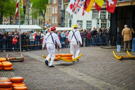 Téléchargez les photos : ALKMAAR, THE NETHERLANDS - APRIL 29, 2022: Cheese carriers walking with cheeses at famous Dutch cheese market in Alkmaar, the Netherlands - en image libre de droit