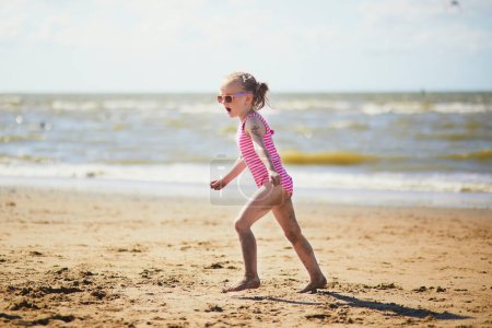 Preschooler girl having fun on the sand beach at sea coast in Noordwijk, the Netherlands. Outdoor summer activities for kids