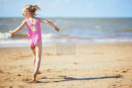 Preschooler girl having fun on the sand beach at sea coast in Noordwijk, the Netherlands. Outdoor summer activities for kids