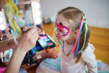 Photo for Children face painting. Artist painting little preschooler girl like unicorn on a birthday party. Creative activities for kids - Royalty Free Image