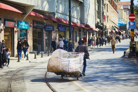 Photo for ISTANBUL, TURKEY - APRIL 24, 2023: Turkish man is carrying a big sack on a barrow in street - Royalty Free Image