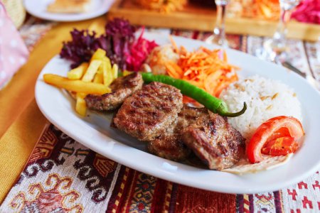 Photo for Delicious Turkish kofta served with rice and vegetables in a restaurant of Istanbul, Turkey. Kofta is a family of meatball or meatloaf dishes of Balkan, Middle Eastern, South Caucasian cuisines - Royalty Free Image
