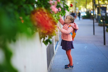 Téléchargez les photos : Adorable fille préscolaire avec sac à dos d'école s'amusant dans une rue un jour d'automne - en image libre de droit