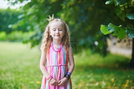 Téléchargez les photos : Jolie fille préscolaire en couronne de princesse dans le parc ou la forêt un jour d'été. Activités de plein air pour enfants - en image libre de droit