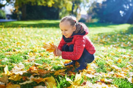 Photo for Adorable preschooler girl enjoying nice and sunny autumn day outdoors. Happy child gathering autumn leaves in Paris, France. Outdoor fall activities for kids - Royalty Free Image
