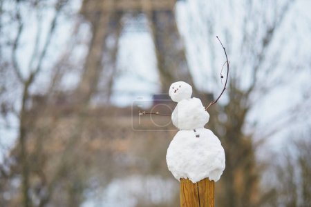 Photo for Funny little snowman and the Eiffel tower on a day with heavy snow - Royalty Free Image