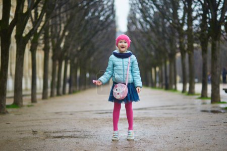Photo for Cheerful preschooler girl having fun on a street of Paris, France in the beginning of spring on a rainy day - Royalty Free Image