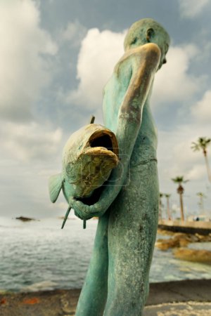 Foto de CHIPRE, PAPHOS-22 MARZO: Paphos es una ciudad costera en el suroeste de Chipre, se encuentra en la costa mediterránea. Vista de la escultura de pescador el 22 de marzo de 2023, Chipre, Paphos. - Imagen libre de derechos