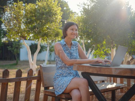 Photo for Happy young asian woman with laptop resting outdoors in tiny house in summer garden, weekend away and remote office idea, early morning. Tiny houses and Small Living concept. - Royalty Free Image