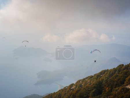 Paragliding in sky. Paraglider tandem flying over sea and mountains in cloudy day. view of paraglider and Blue Lagoon in Oludeniz, Turkey. Extreme sport. Landscape