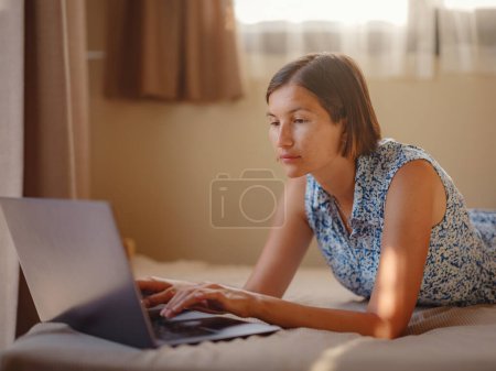 Photo for Happy young asian woman with laptop resting in bedroom in tiny house, weekend away and remote office idea. Tiny houses and Small Living concept. - Royalty Free Image