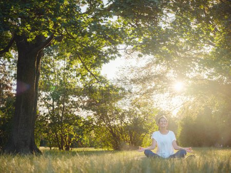 Jeune femme asiatique faisant de la méditation le matin ou le soir au parc, femme en bonne santé se détendre et pratiquer le yoga au parc de la ville. Mindfulness, destress, Habitudes saines et concept d'équilibre