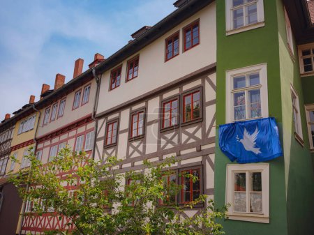 viaje de primavera a Europa. vista panorámica a la fachada de antiguas casas históricas en algún lugar de la ciudad de Erfurt, bandera azul con una paloma de paz que los residentes de la casa colgaban en su fachada