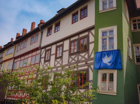 spring trip to Europe. scenic view to facade of old historic houses somewhere in Erfurt city, blue flag with a dove of peace that residents of house hung on their facade