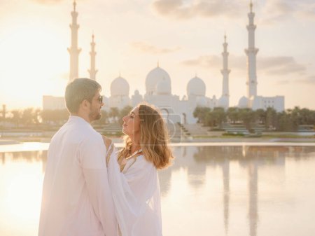 Travel to the United Arab Emirates, Abu Dhabi. Arab couple visiting park near Grand Mosque in Abu Dhabi wearing traditional dress.