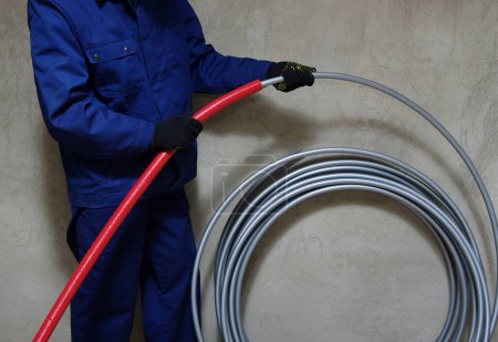 Téléchargez les photos : Plombier installant des tuyaux en plastique, faisant des travaux d'entretien pour les systèmes d'eau et de chauffage. - en image libre de droit