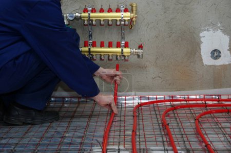 Foto de Fontanero instalación de colector y tubos de plástico para el sistema de calefacción por suelo radiante - Imagen libre de derechos