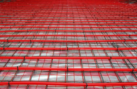 Téléchargez les photos : Chauffage au sol dans la construction d'une maison neuve avec tuyaux en plastique rouge sur un réflecteur métallisé - en image libre de droit