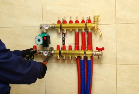 Photo for Plumber installing collector and plastic pipes for heating system for underfloor heating - Royalty Free Image